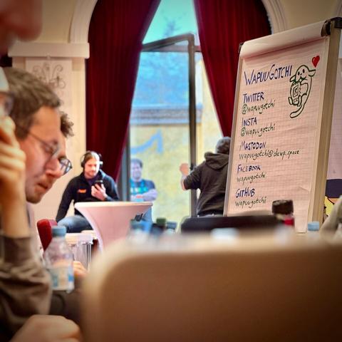 A flip chart with a Wapuu drawing on it, which also shows the social media handles
