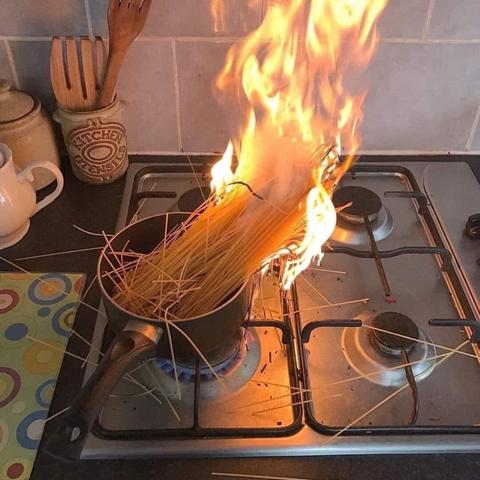 A saucepan of dry uncooked spaghetti on fire