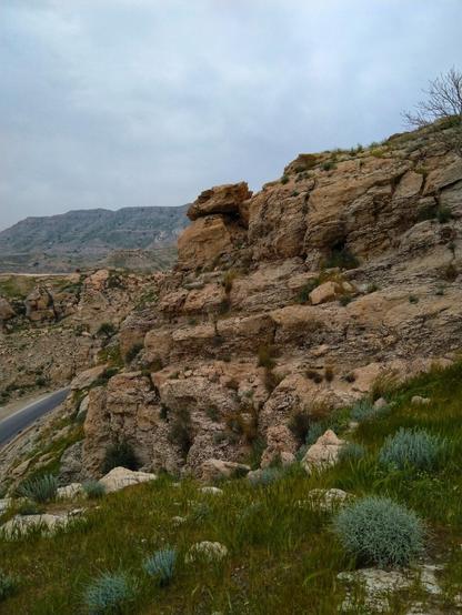 چشم‌اندازی از بالای کوه. تصویر شامل آسمان، کوه و سبزه است.