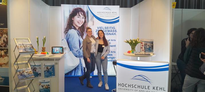Zwei Studentinnen der Hochschule posieren am Messestand.