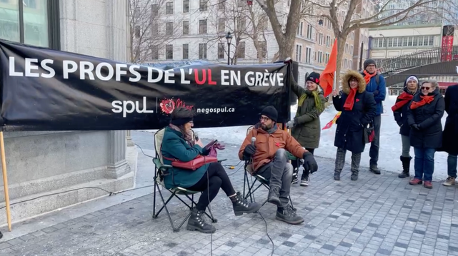 Une femme et un homme sont assis sur des chaises pliantes dehors avec une banderole "Les profs de l'UL en grève".