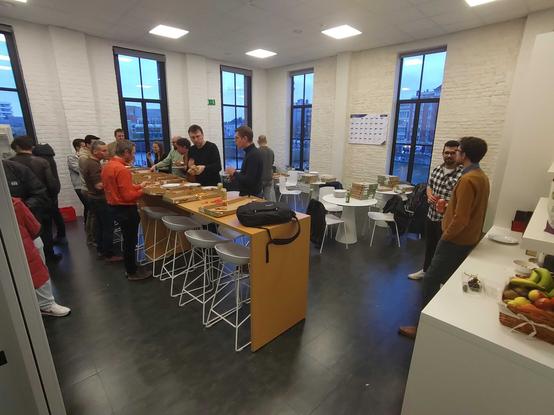 Participants of the JUG in the kitchen of Sweet Mustard with drinks and pizza