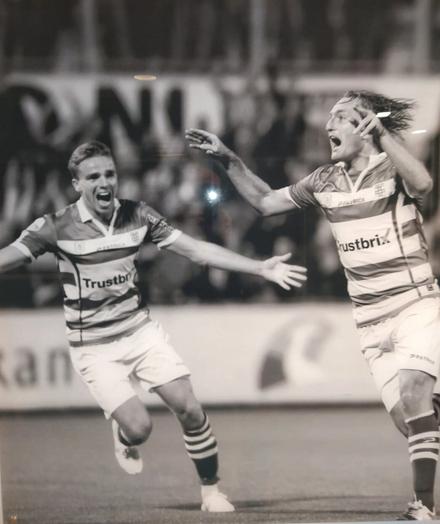 Foto, zwart wit, van twee juichende voetballers op de voorgrond