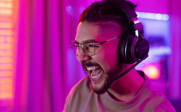 A happy man wearing glasses and the new Turtle Beach Stealth Pro Wireless Gaming Headset.