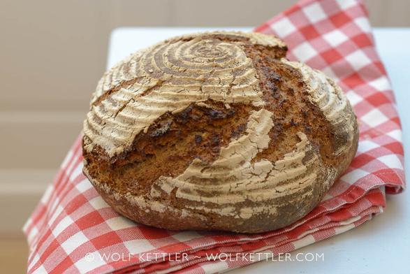 A loaf of Austrian sourdough rye bread arranged on a red and white chequered tablecloth.