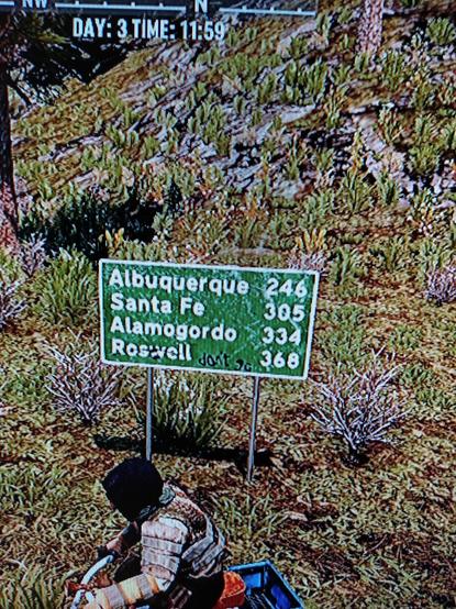 Screen shot of a road side sign with distances to several cities listed from the game 7 Days to Die.