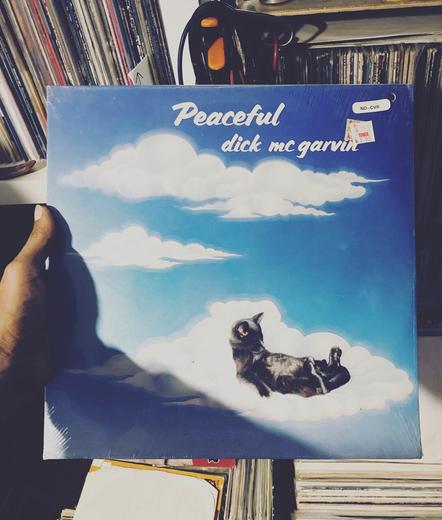 Dick McGarvin “Peaceful” album cover art with a cat chillin on a cloud way up in the sky.