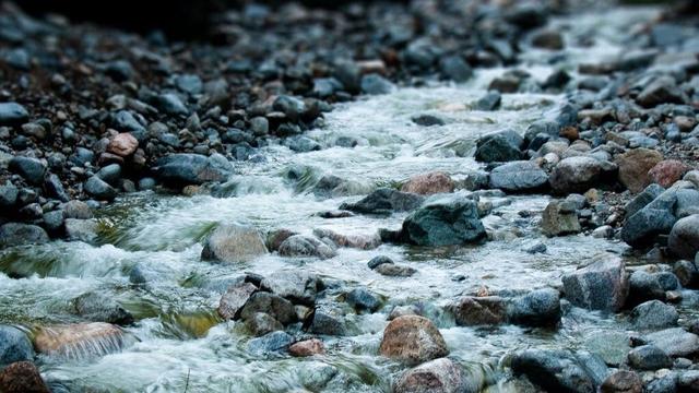 photo of a stream flowing over stones and pebbles