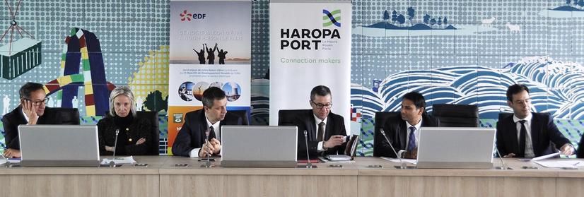 Photo produite par le service de Communication. Mise en scène de signature d'une convention de partenariat entre HAROPA PORT et EDF.

Une table extrêmement longue barre la photographie dans un arrangement qui suit les représentations de la Cène au Quattrocento.

Les cinq hommes ont l'air contents. La seule femme croise les bras.