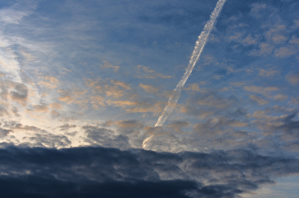 Contrail and spring clouds, rising sun. Warm morning.