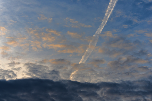 Contrail and spring clouds, rising sun. Warm morning.