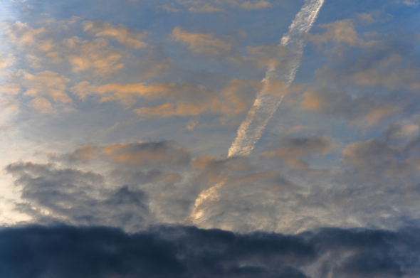 Contrail and spring clouds, rising sun. Warm morning.