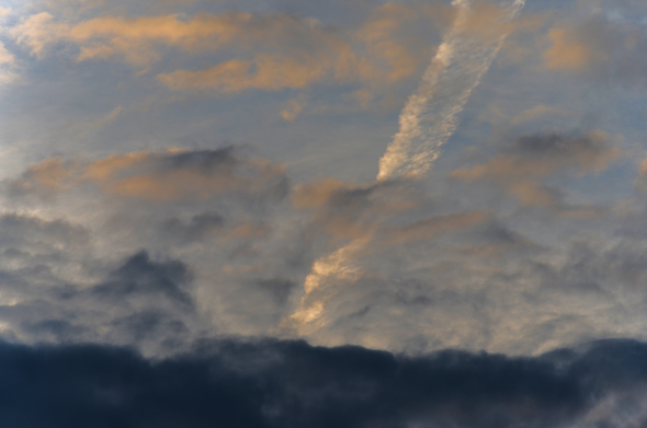 Contrail and spring clouds, rising sun. Warm morning.