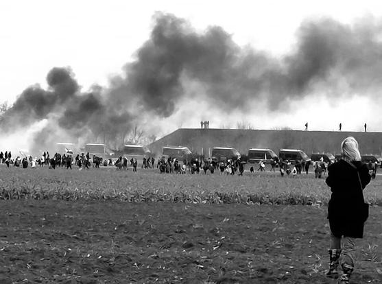 Fumée noire au-dessus d'un alignement de cars devant une digue de mégabassine - photo par Nad Iam le samedi 25 mars 2023 à Sainte-Soline