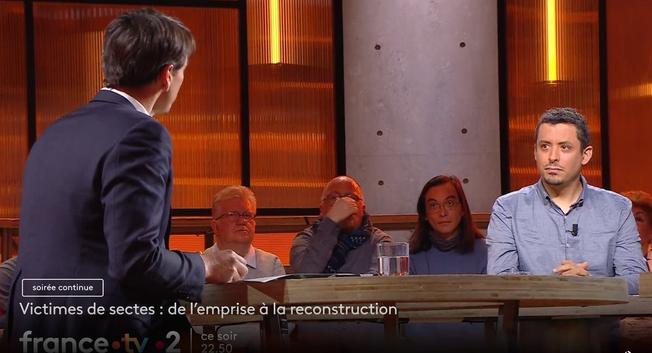 Capture d'écran de moi même sur le plateau TV de France 2 avec le présentateur et le public en arrière plan