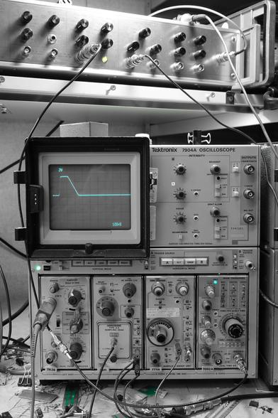 A photo of an analog oscilloscope and signal source, with a green phosphor color pop