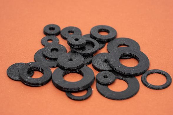 3D printed, black washers on an orange background.