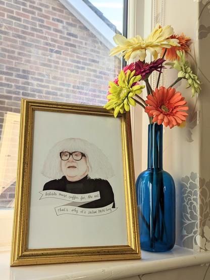Watercolour illustration of Danny DeVito as Frank Reynolds as the "art critic" Ango Gablogian in It's Always Sunny in Philadelphia. He wears a Andy Warhol style white wig and glasses with thick black frames, and a black turtleneck. 

In a ribbon banner under him it reads "artists must suffer for the art. That's why its called PAIN-ting"

The picture is in a gold frame on a windowsill.