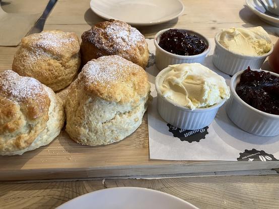 Four warm scones with strawberry jam and cream.