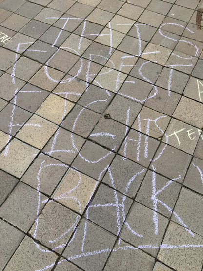 This Forest Fights Back written in lilac chalk on a concrete block sidewalk in front of a #DOJ building in #DC