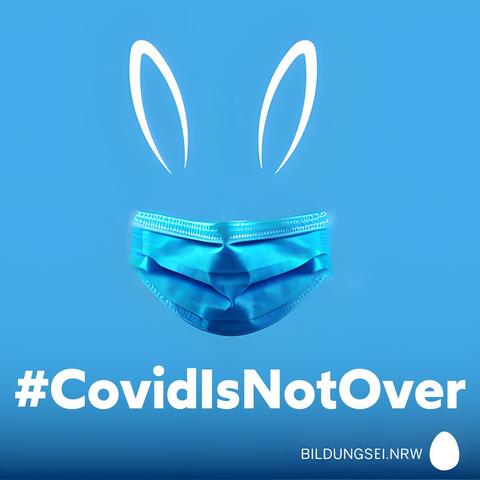 stilisierte Hasenohren und eine chirurgische Maske als Atemschutz. Der Osterhase geht auf Nummer sicher. Text: Covid is not over. Logotype: Bildungs Ei NRW