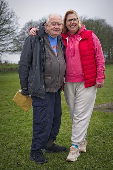 Two people. Man and woman in field with arms around each other.