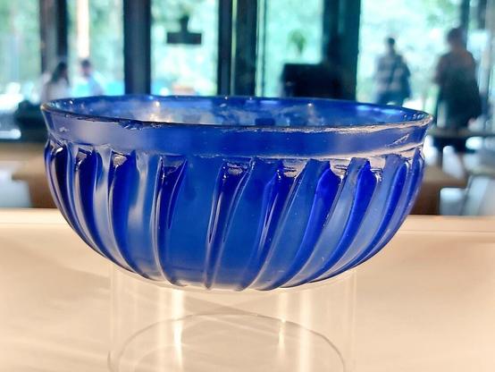 The picture shows a ribbed bowl made of translucent dark blue glass.