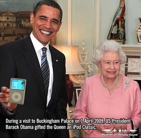 In a file photo from 1 April 2009, Barack Obama stands next to the Queen inside Buckingham Palace. She wears a pink dress and is smiling. He holds the silver iPod Classic which appears to be playing a hip hop track by Ol' Dirty Bastard. A headline at the bottom reads "During a visit to Buckingham Palace on 1 April 2009, Barack Obama gifted the Queen an iPod Classic. But how big was its hard drive??
