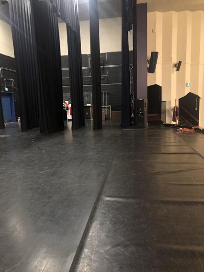 An empty theatre stage. Dance flooring is visible on part of it.