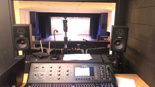 View of the stage from the tech booth. A Midas M32 console is visible in the foreground.