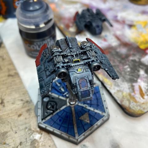 An Arvus lighter model from the Aeronautica Imperialis table top war game,painted in greys and reds with yellow and metal highlights. Various hobby stuff in background.