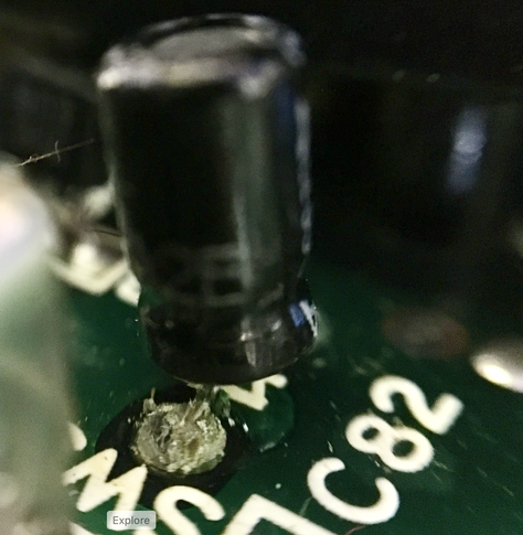 Extreme close up of the mainboard of an Olivetti M10. Image is a capacitor that is failing. Green corrosion on the legs.