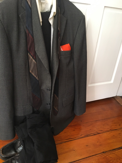 cis male suit and tie on a hanger on an open door's knob