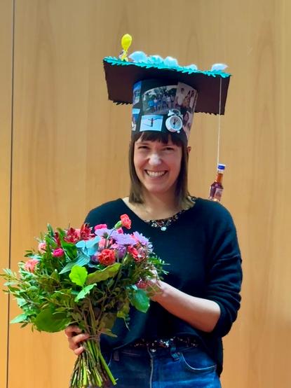 Photo of Jule Radtke after the defense wearing her PhD hat and holding flowers.