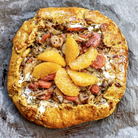 Die fertige Tarte auf dem Blech. 
Der Rand ist etwas zur Mitte umgeschlagen, in der Mitte eine Blüte aus Orangenfilets
