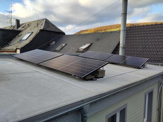 Ein Flachdach mit vier aufgeständerten Photovoltaik Modulen.
