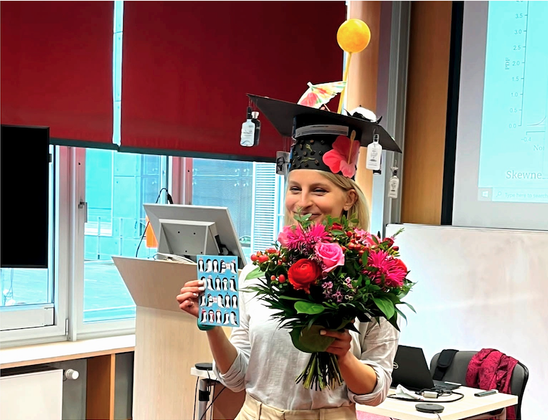 Photo of Iana Strigunova wearing her PhD hat and holding flowers.