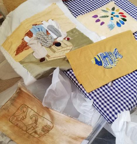 Four embroidered pieces, all different techniques, lying helter-skelter near each other, waiting to be mounted.