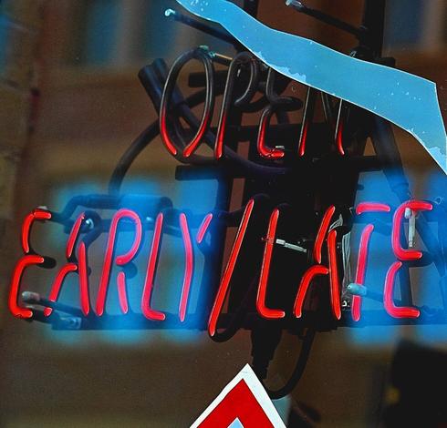 A neon sign in a window that reads "Open Early/Late."