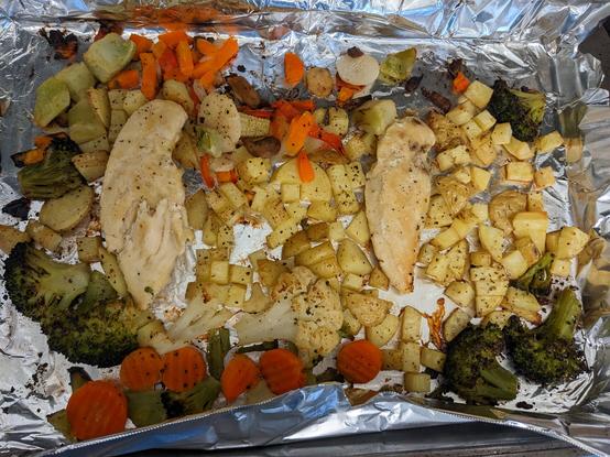 A sheet pan with veggies and chicken after cooking in the oven.