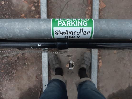 Close up of sticker on bike stand. Sticker says:

RESTRICTED PARKING
steamroller 
ONLY