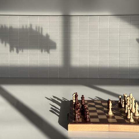 a chessboard casting a strange shadow in a sunbeam.