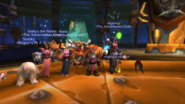 A screenshot from world of warcraft featuring a dwarf, two humans and a draenei waving to the camera after the boss fight in Gnomeregan. A polar bear is showing it's butt.