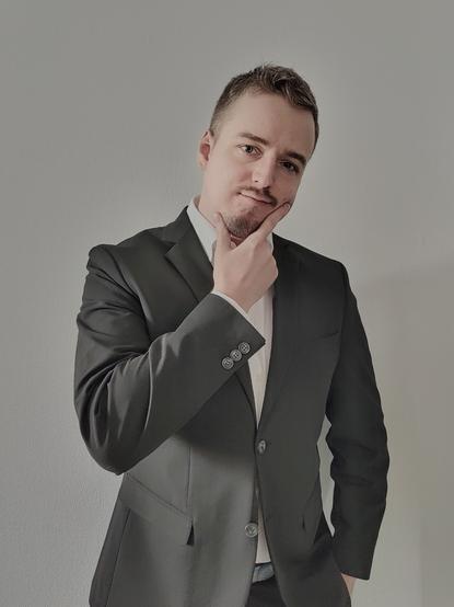 Portrait of a man in a suit holding his hand against his face.