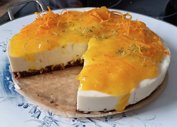 die fertige Torte wurde angeschnitten.
Man sieht den dunklen Boden, die helle Creme und oben die orangene Sauce mit der Garnierung.