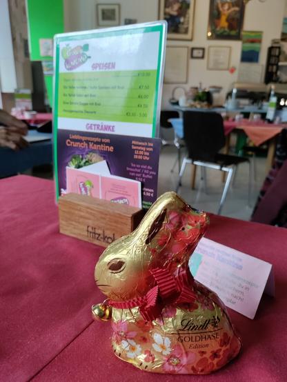 The inside of the restaurant with a point of view from a table looking at a menu and a golden chocolate rabbit.