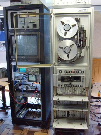A large rack of an AMPEX FR-900 reel tape recorder, and another rack containing a CRT and more electronics.