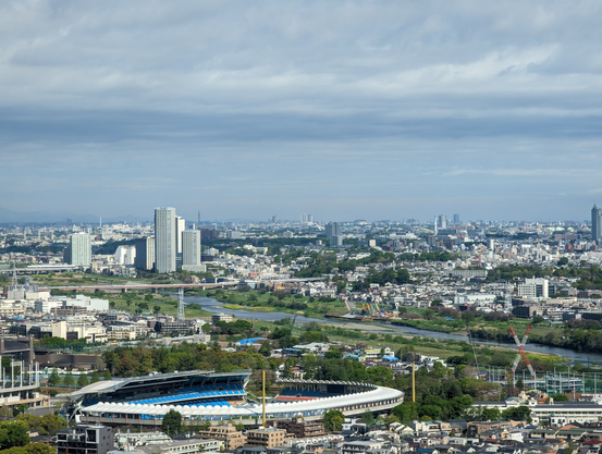 A view of the Tama River between Kawasaki and Tokyo. There's a stadium in the foreground and skyscrapers in the distance.