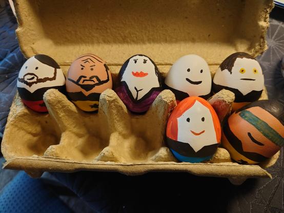 Sieben bemalte Eier in einem Eierkarton. Sie sind Figuren aus Star Trek Next Generation nachempfunden: Riker, Worf, Deanna Troi, Picard, Data, Beverly Crusher und Geordi LaForge.