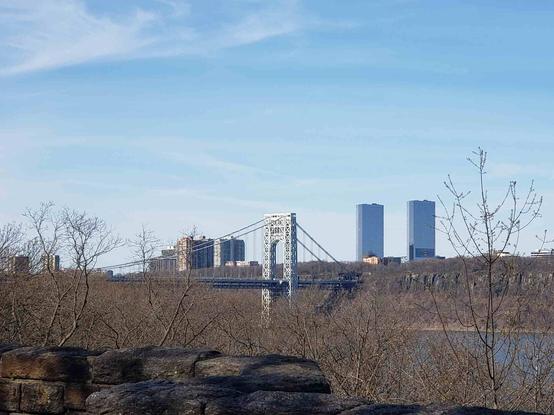 It's a steel suspension bridge over the Hudson River in the morning sunlight, under a cloud-streaked sunny light blue sky.